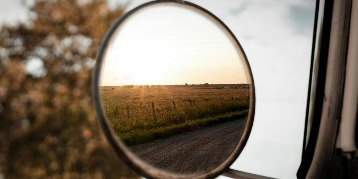 Side mirror of a car, reflecting a field