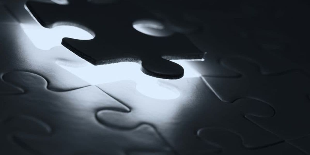 Piece of a puzzle, illuminated in front of other puzzles